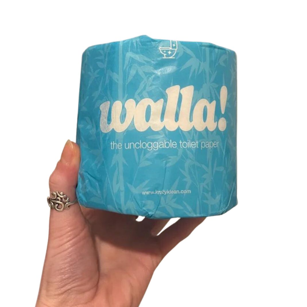 Hand holding a blue roll of Walla! brand 'uncloggable' toilet paper.